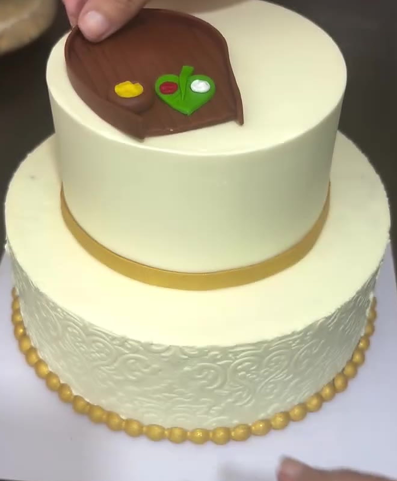 Two-tier ivory wedding cake with gold detailing